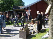 Rustningsmakare med Alruna hantverk i bakgrunden
